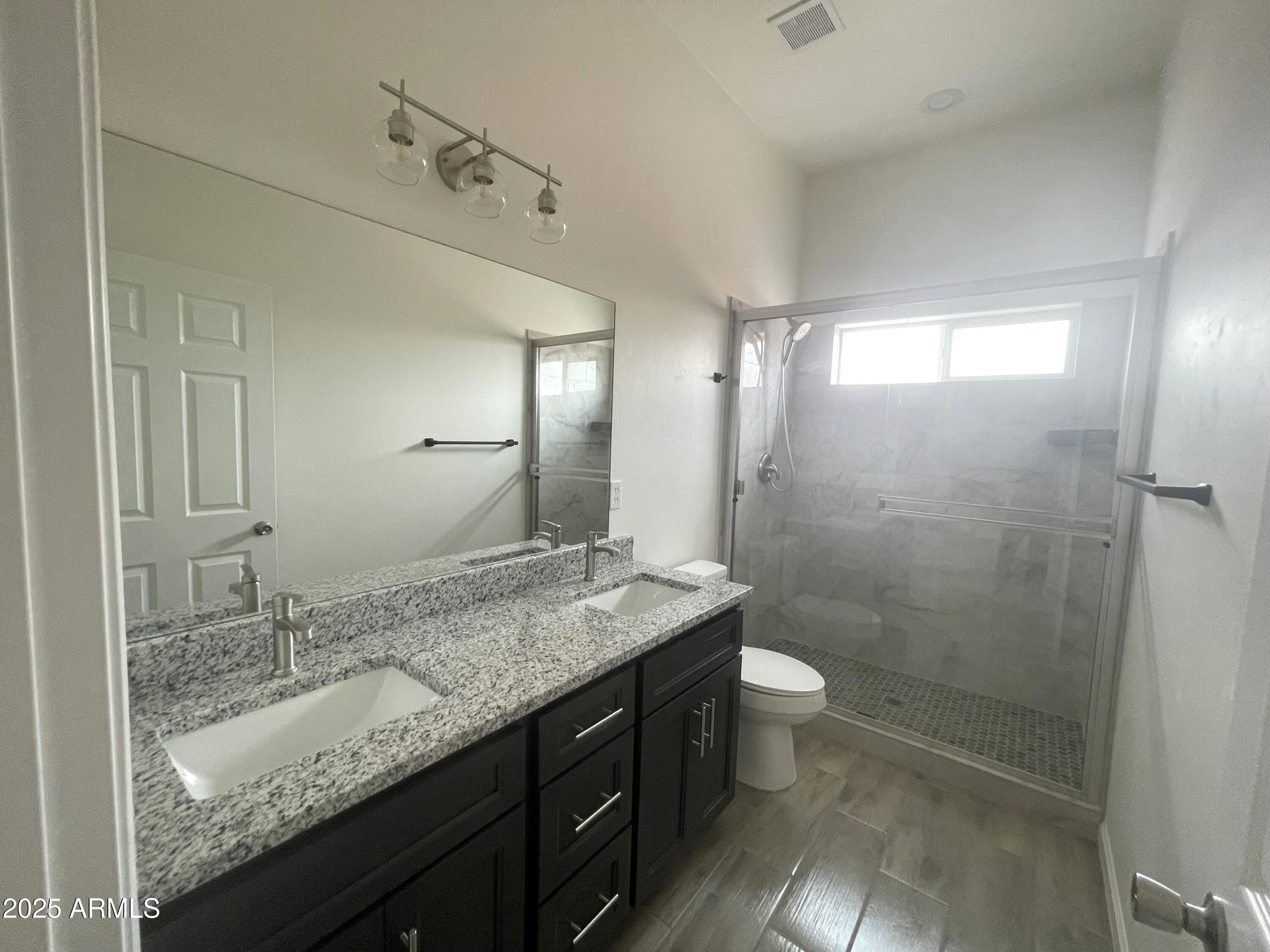 1825 Via Nueva Zelandia Rio Rico, AZ 85648 - Photo 15 of 20 a bathroom with a granite countertop sink a toilet a mirror and shower