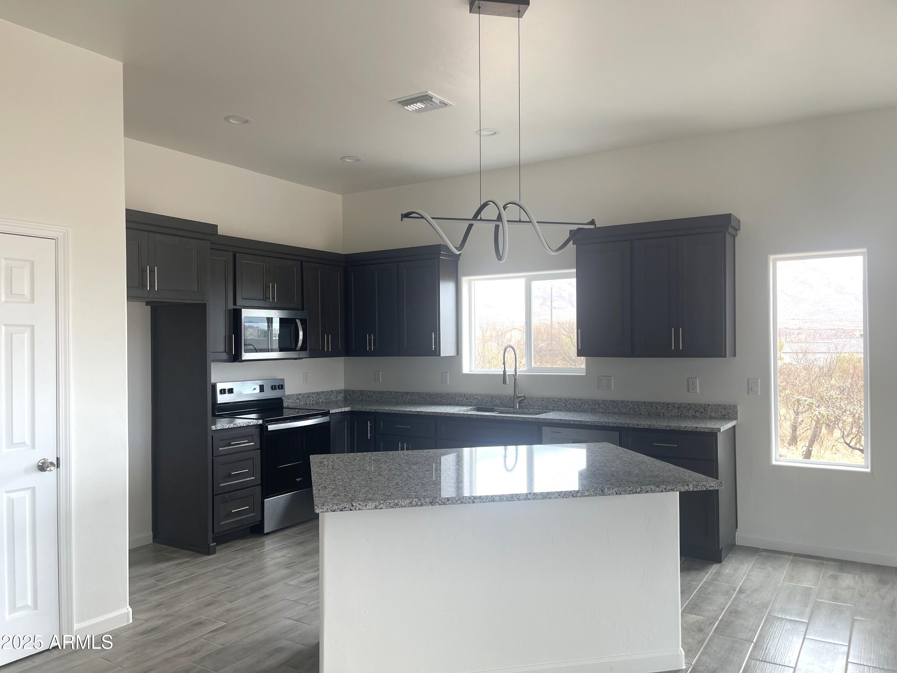 1825 Via Nueva Zelandia Rio Rico, AZ 85648 - Photo 8 of 20 a kitchen with kitchen island a sink stainless steel appliances and window