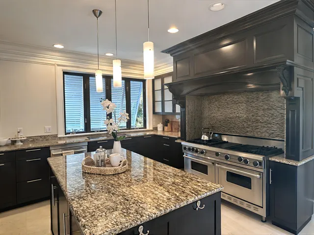 a kitchen with stainless steel appliances kitchen island granite countertop a refrigerator a stove and a sink