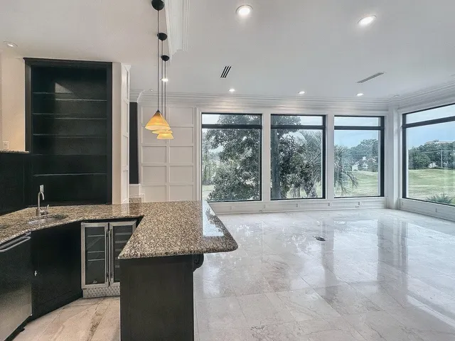 a living room with stainless steel appliances furniture a fireplace and a open kitchen view
