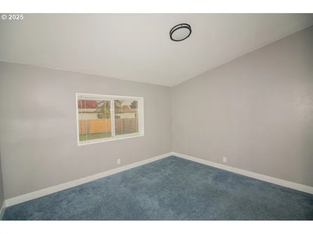 a view of an empty room with wooden floor and chandelier
