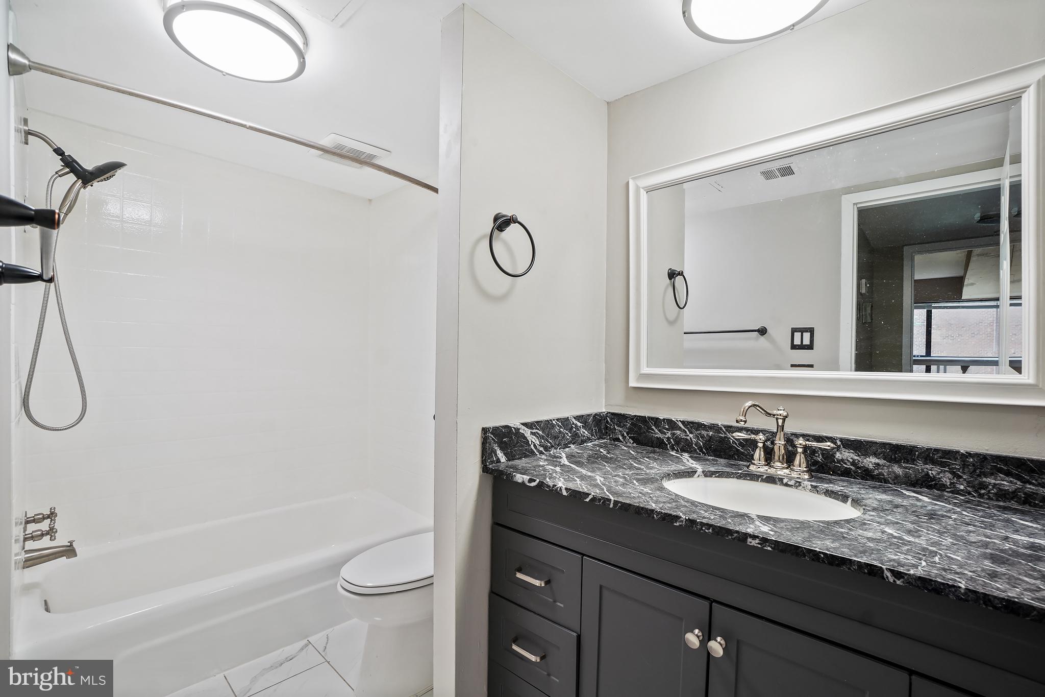 8487 Greenbelt Road Greenbelt, MD 20770 - Photo 15 of 29 a bathroom with a granite countertop sink toilet and shower