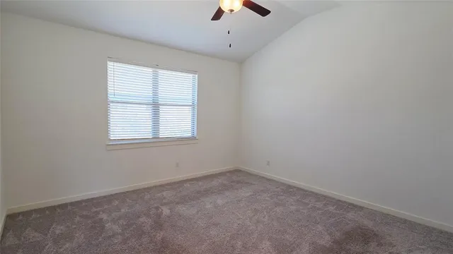 an empty room with chandelier fan and windows