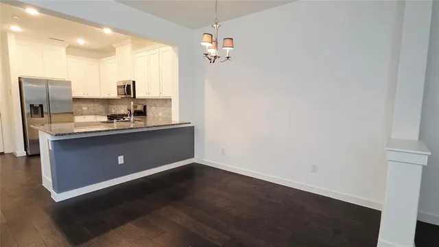 a room with kitchen island a sink wooden floor and glass door