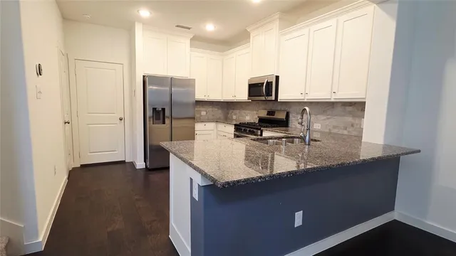 a kitchen with stainless steel appliances granite countertop a sink a stove and a refrigerator