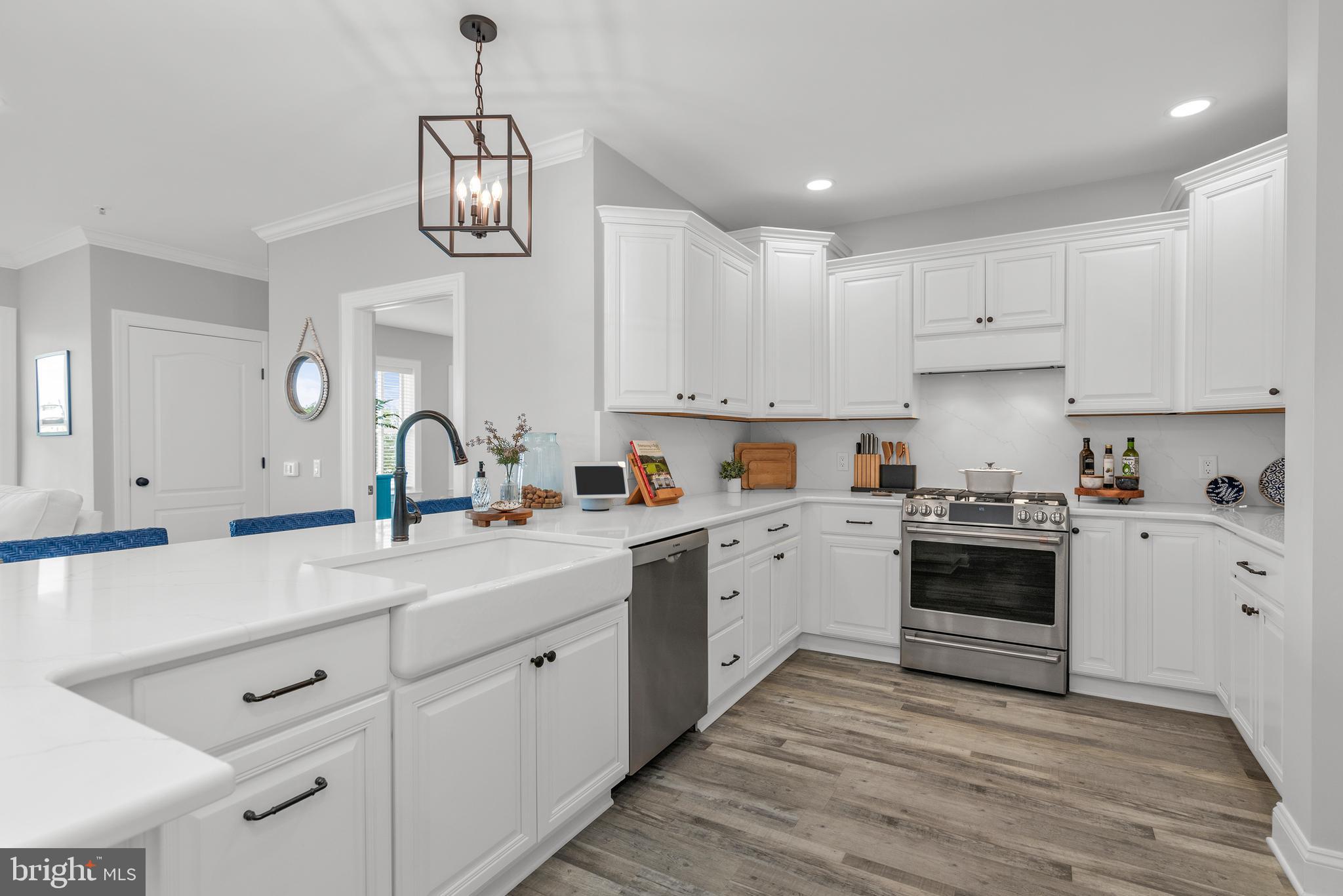 301 Muir Street, Unit 303 Cambridge, MD 21613 - Photo 15 of 36 a kitchen with a sink dishwasher a stove and white cabinets with wooden floor