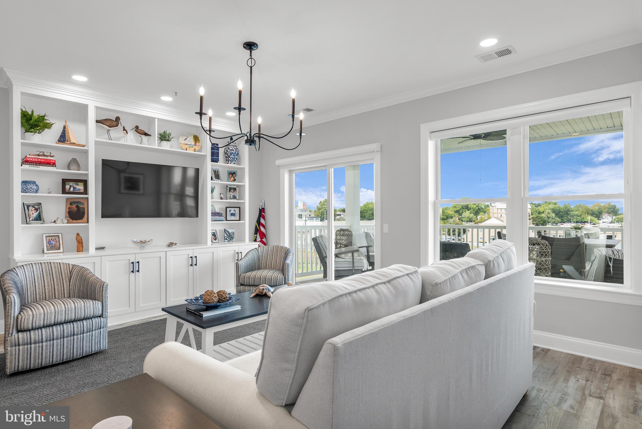 301 Muir Street, Unit 303 Cambridge, MD 21613 - Photo 9 of 36 a living room with furniture flat screen tv and a chandelier