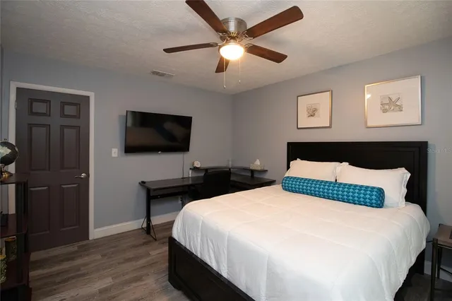 a bedroom with a bed and a flat tv screen on dresser