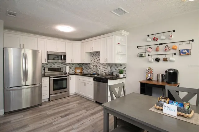 a kitchen with a refrigerator a stove a sink dishwasher with a dining table and chairs