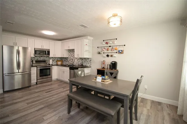 a kitchen with stainless steel appliances a dining table chairs and refrigerator