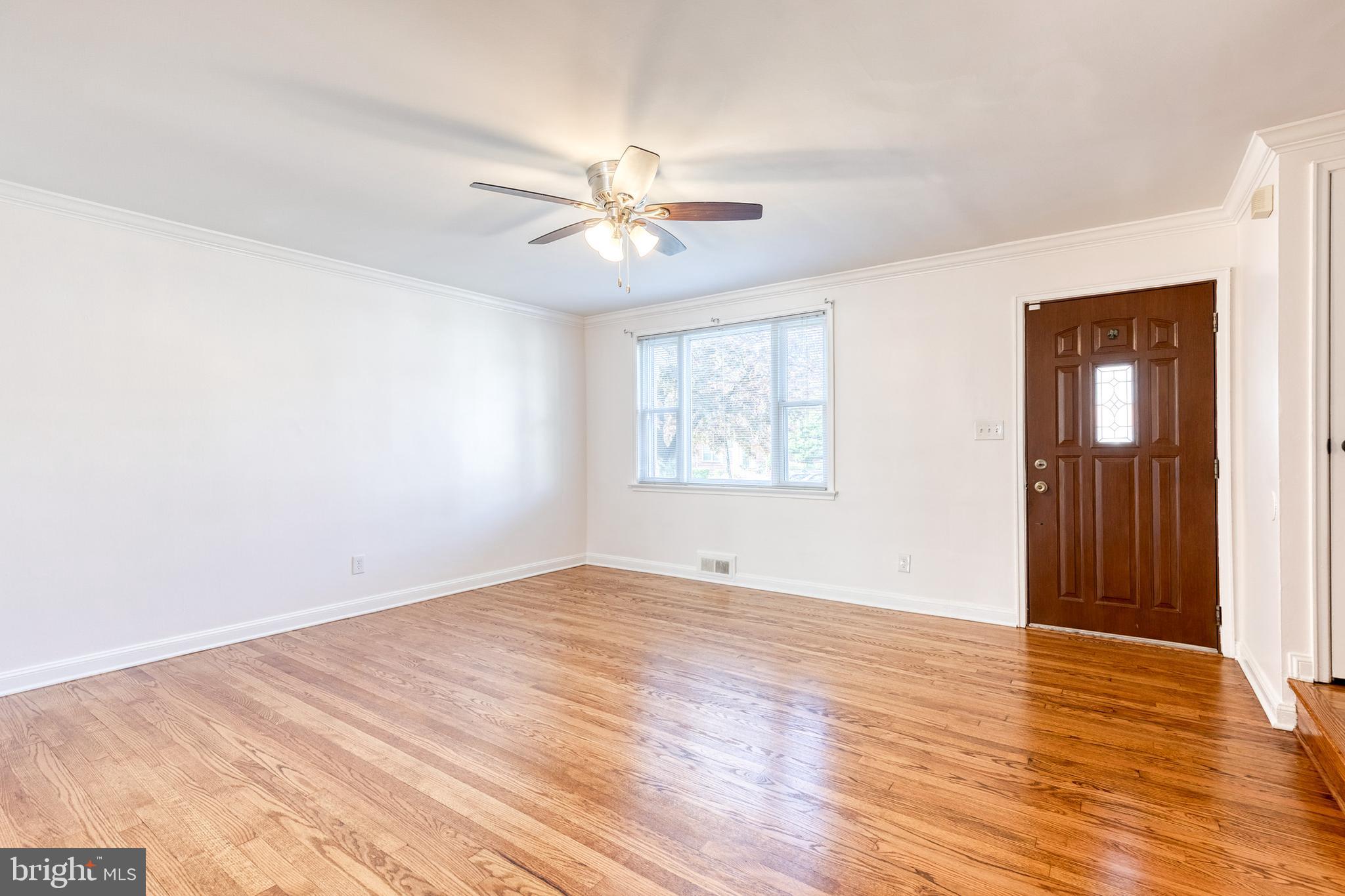 2012 Northbourne Road Baltimore, MD 21239 - Photo 10 of 35 an empty room with wooden floor chandelier fan and windows