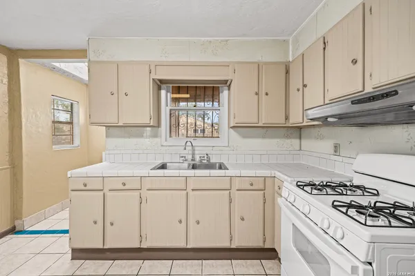 a kitchen with white cabinets sink and stove