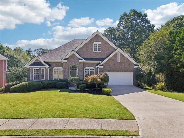 a front view of a house with a garden and trees