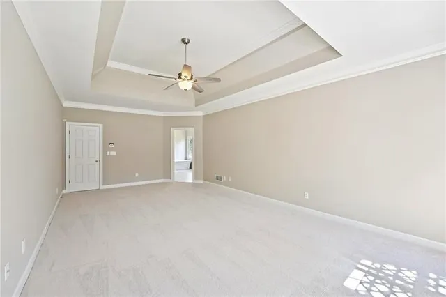 an empty room with a chandelier fan and windows