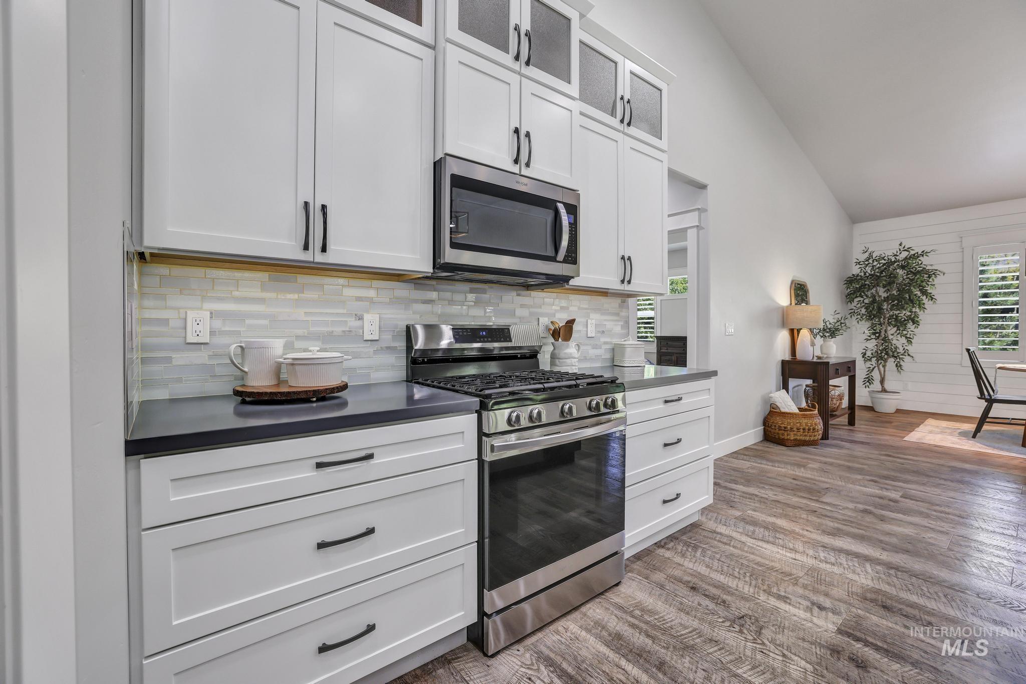 1937 Tamarack Loop Twin Falls, ID 83301 - Photo 16 of 50 Kitchen featuring white shaker cabinetry with dark pulls, stainless steel appliances, dark countertops, and a subway tile backsplash