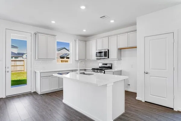 a kitchen with a sink a stove a refrigerator and white cabinets