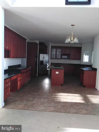 a kitchen with kitchen island granite countertop a stove top oven a sink dishwasher and cabinets with wooden floor