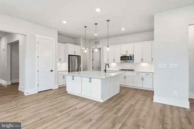 a large white kitchen with a stove a sink dishwasher and a refrigerator with wooden floor