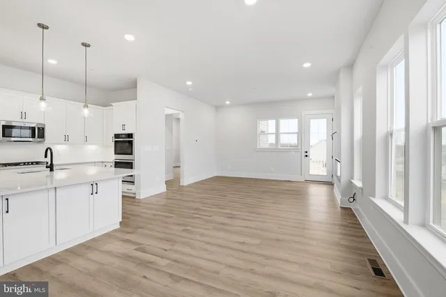 a large kitchen with white cabinets and wooden floor