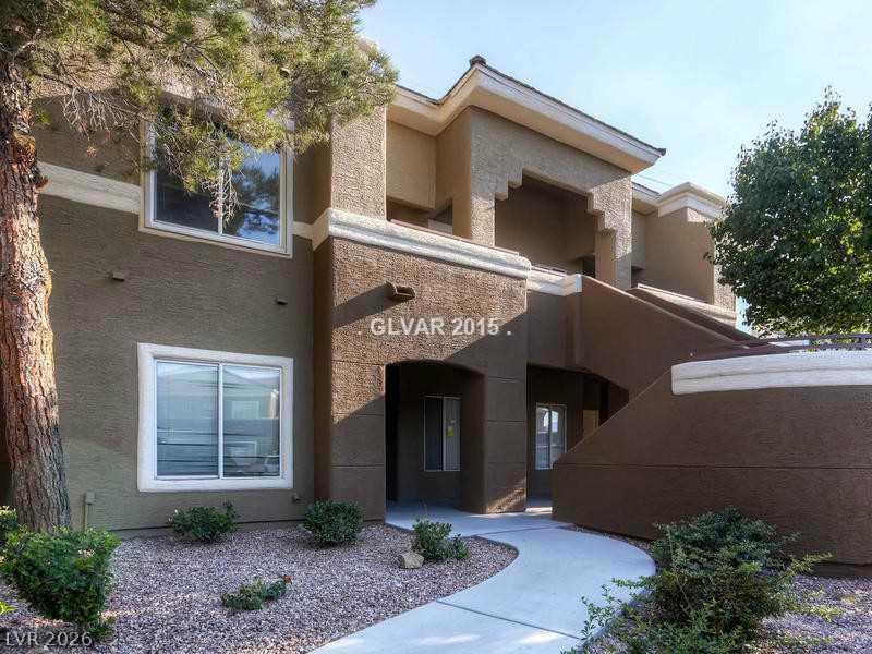 8070 West Russell Road, Unit 2120 Las Vegas, NV 89113 - Photo 1 of 11 A concrete walkway winds past low-maintenance desert landscaping toward the stucco exterior of this multi-level building.