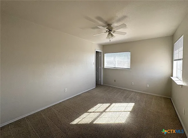 an empty room with windows and fan