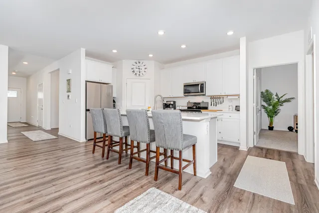 a kitchen with stainless steel appliances a dining table chairs stove and refrigerator