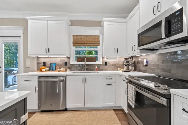 a kitchen with stainless steel appliances white cabinets and a stove top oven