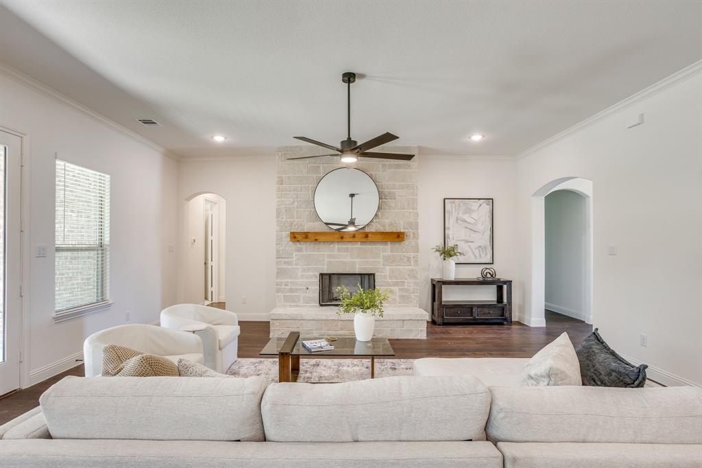 608 Tay Tay Way Springtown, TX 76082 - Photo 6 of 40 Stone-clad fireplace with a wood mantle, ceiling fan with integrated lighting, recessed lighting, arched entryways, and wood-finish flooring