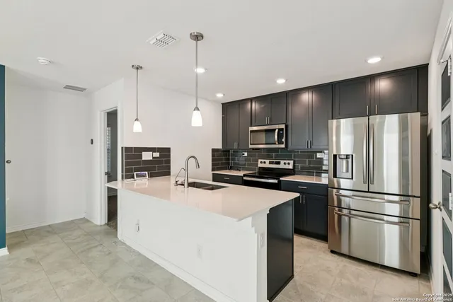 a kitchen with kitchen island a refrigerator a sink stainless steel appliances and cabinets