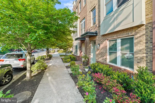 front view of a brick house with a large window and potted plants