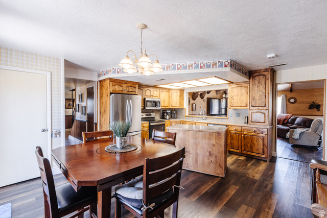 1470 Redwood Tree Street St. George, UT 84790 - Photo 4 of 53 Open-concept kitchen and dining area featuring wood-finish flooring, warm wood cabinetry, stainless steel appliances, and a central island with countertop space
