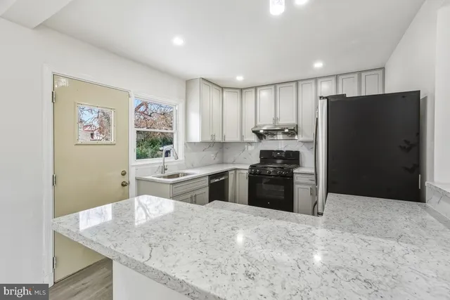 a kitchen with stainless steel appliances kitchen island granite countertop a refrigerator and a sink