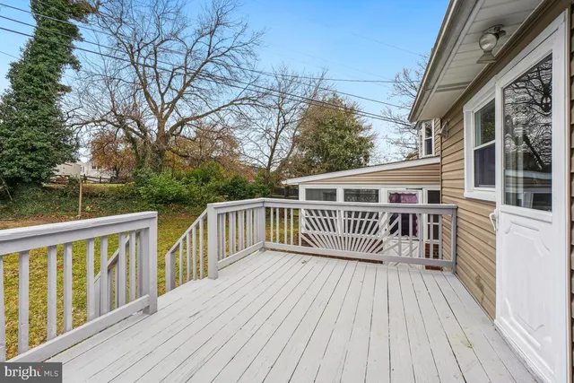 a balcony with wooden floor and fence next to a yard