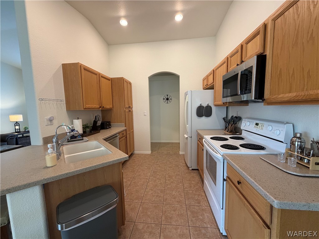 2416 North Ridge Avenue Bullhead City, AZ 86429 - Photo 14 of 33 Kitchen with stainless steel appliances, arched walkways, a peninsula, light stone countertops, and a breakfast bar area