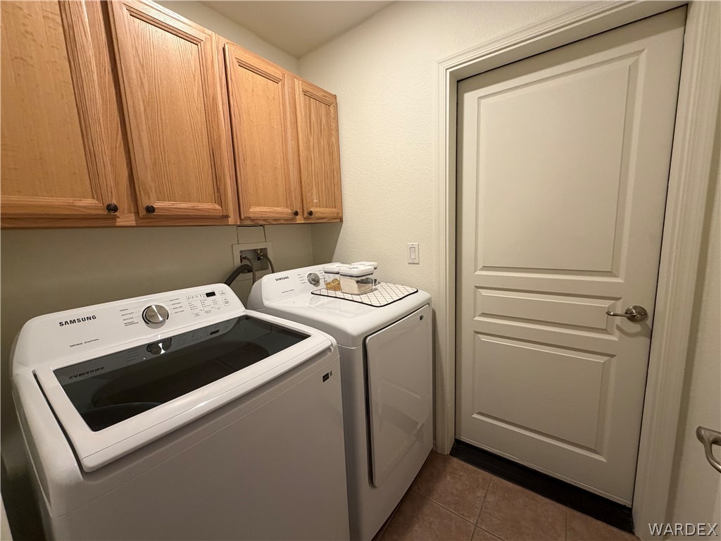 2416 North Ridge Avenue Bullhead City, AZ 86429 - Photo 25 of 33 Laundry room with washer and dryer, dark tile patterned flooring, and cabinet space