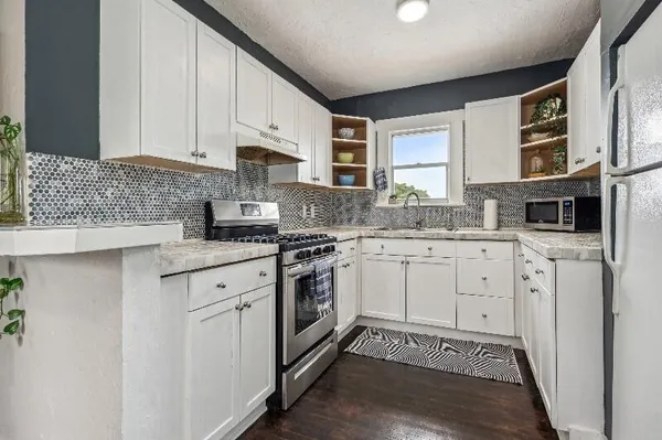 a kitchen with granite countertop white cabinets and white appliances