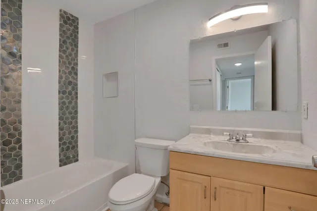a bathroom with a granite countertop toilet sink and mirror