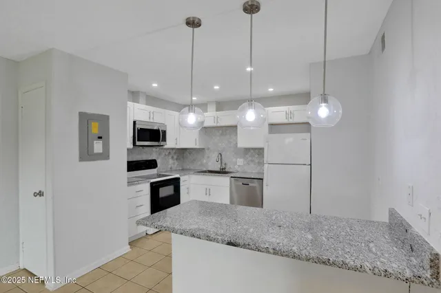 a large kitchen with kitchen island a sink stainless steel appliances and a chandelier