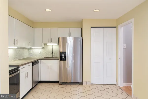 a kitchen with stainless steel appliances white cabinets and a refrigerator