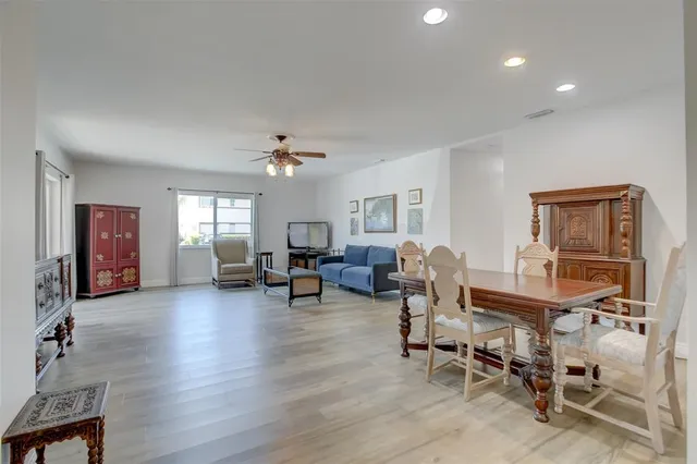 a living room with furniture and a dining table with wooden floor