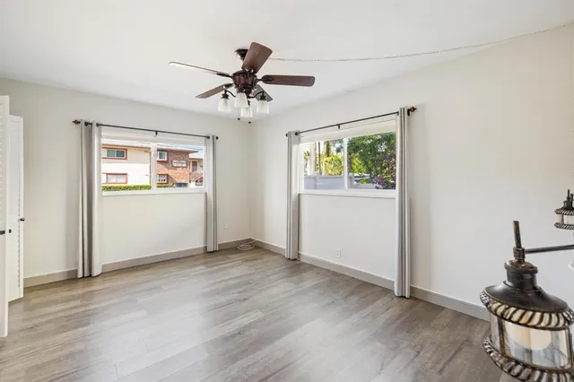 a view of an empty room with a window and wooden floor
