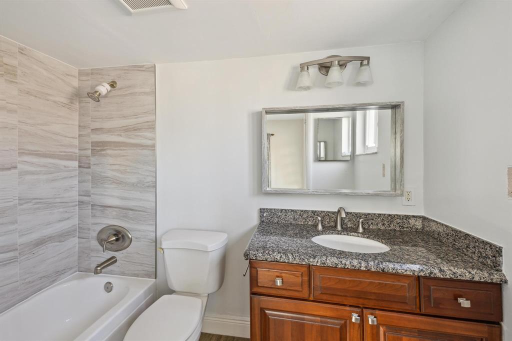 1450 North Riverside Drive, Unit 101 Pompano Beach, FL 33062 - Photo 22 of 52 a bathroom with a granite countertop sink a mirror a bathtub and a toilet