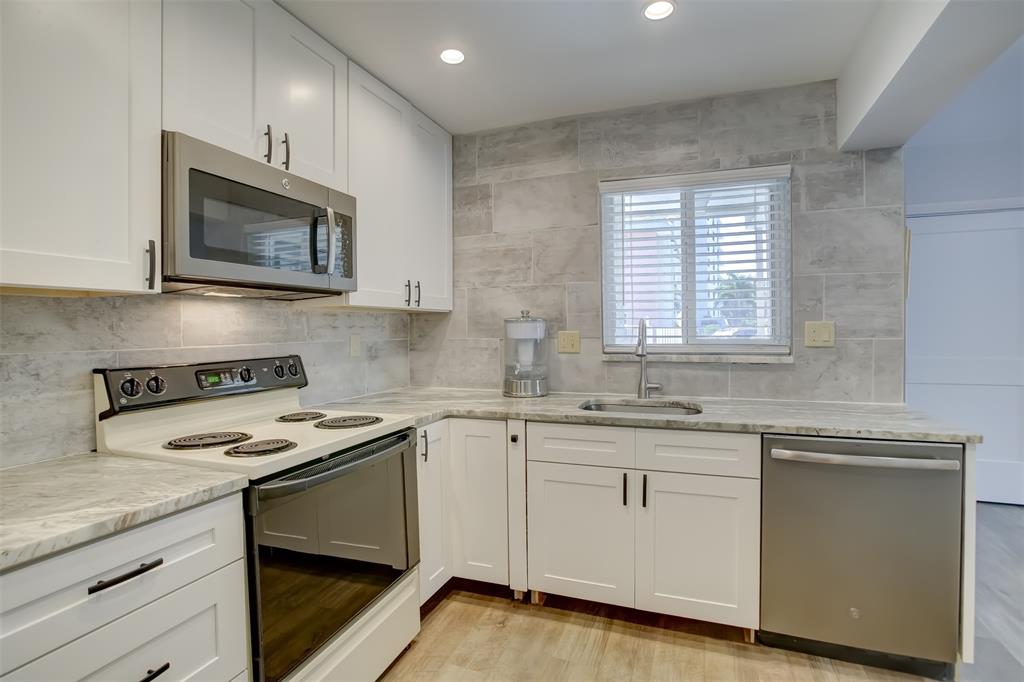 1450 North Riverside Drive, Unit 101 Pompano Beach, FL 33062 - Photo 3 of 52 a kitchen with white cabinets appliances and a sink