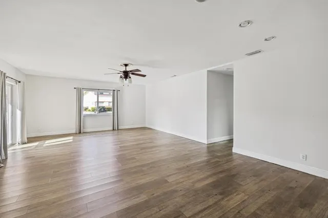 an empty room with wooden floor mirror and windows