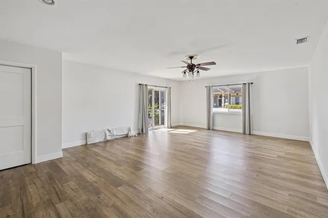 a view of empty room with wooden floor and ceiling fan