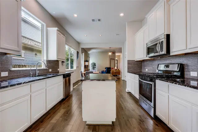 a large kitchen with stainless steel appliances granite countertop a stove a sink dishwasher and a microwave oven with wooden floor