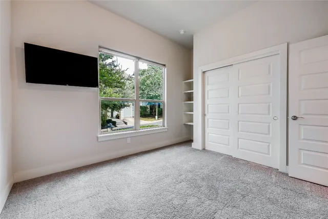 a view of an empty room with a window and a flat screen tv