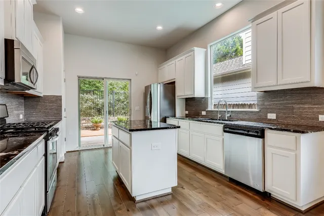 a kitchen with stainless steel appliances granite countertop a stove a sink and a microwave