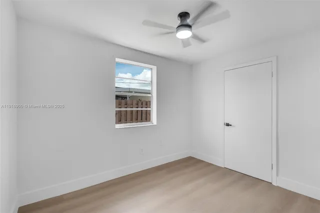 an empty room with windows and fan
