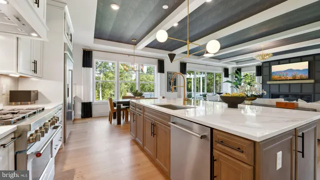 a kitchen with stainless steel appliances granite countertop a stove a refrigerator a kitchen island a stove and white cabinets with wooden floor